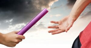 Passing the baton between two relay runners, close-up of their hands
